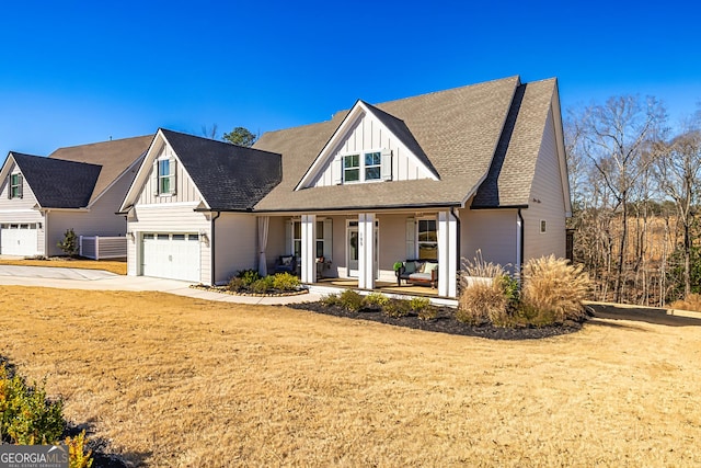 modern inspired farmhouse featuring a garage, concrete driveway, covered porch, board and batten siding, and a front yard