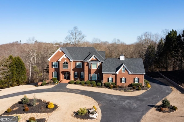 colonial inspired home featuring aphalt driveway and brick siding