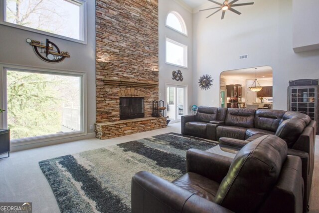 8910 Champion Ct, Ball Ground, GA 30107 - carpeted living room featuring a high ceiling, arched walkways, ceiling fan, and a fireplace