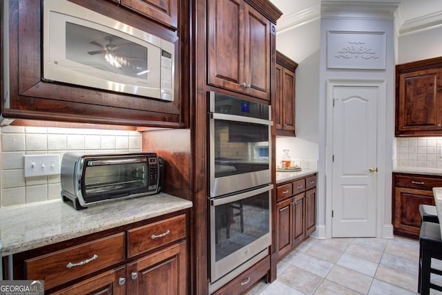 8910 Champion Ct, Ball Ground, GA 30107 - kitchen featuring appliances with stainless steel finishes, decorative backsplash, crown molding, light stone countertops, and light tile patterned floors