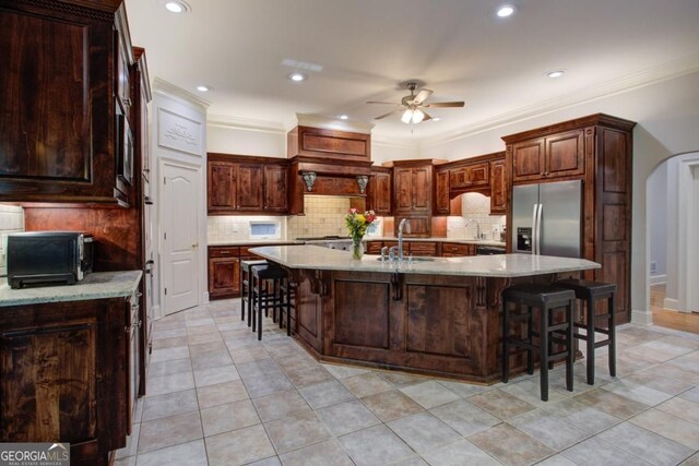 8910 Champion Ct, Ball Ground, GA 30107 - kitchen with stainless steel fridge with ice dispenser, ceiling fan, a kitchen bar, tasteful backsplash, and a large island
