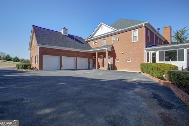 8910 Champion Ct, Ball Ground, GA 30107 - view of property exterior featuring a chimney, an attached garage, brick siding, and driveway