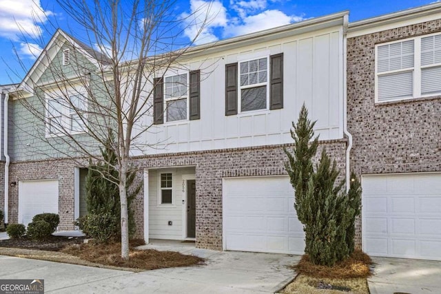 multi unit property with board and batten siding, concrete driveway, brick siding, and an attached garage