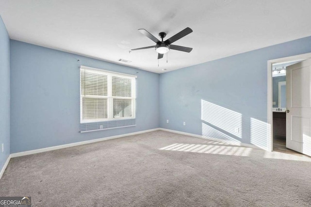 spare room featuring light carpet, ceiling fan, visible vents, and baseboards