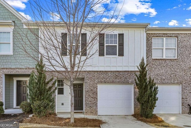 townhome / multi-family property with driveway, brick siding, board and batten siding, and an attached garage