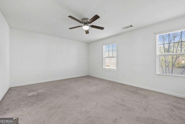 carpeted empty room featuring baseboards, visible vents, and ceiling fan