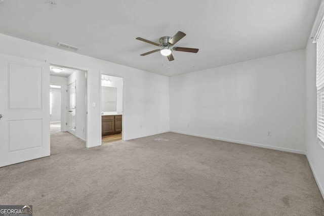 unfurnished bedroom featuring ensuite bathroom, ceiling fan, light colored carpet, visible vents, and baseboards