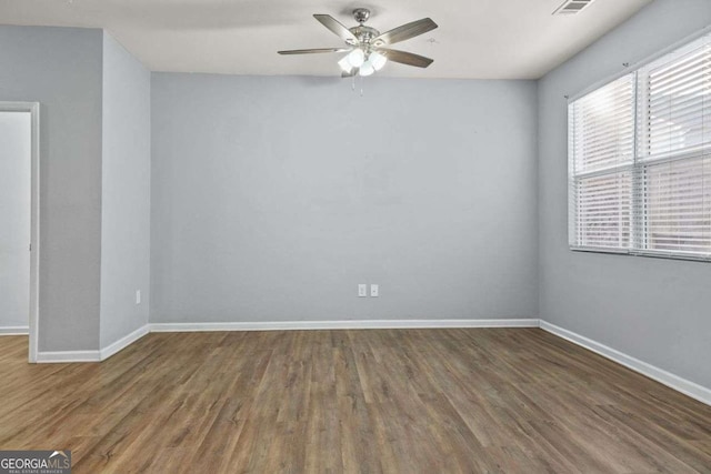 spare room featuring dark wood-style flooring, ceiling fan, and baseboards