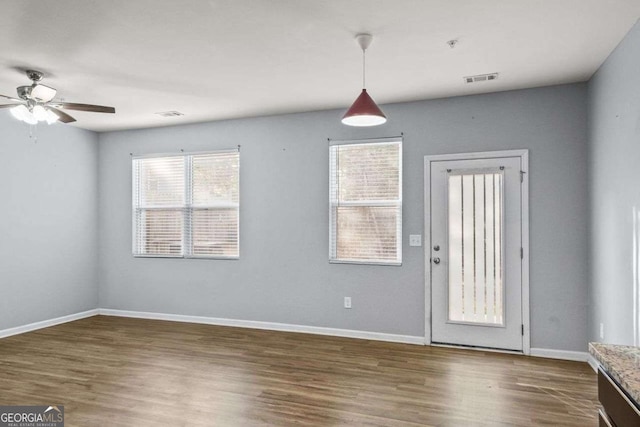 interior space featuring ceiling fan, dark wood-style flooring, visible vents, and baseboards