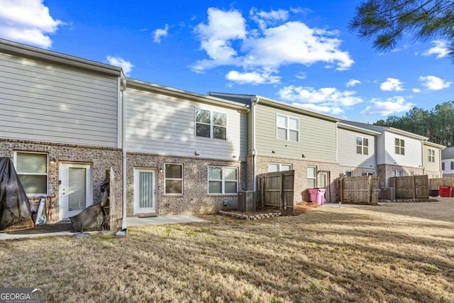 back of property featuring brick siding, a yard, a patio area, fence, and cooling unit