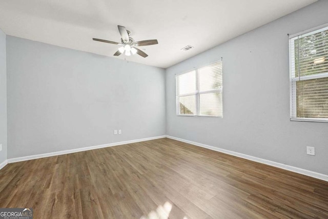 unfurnished room featuring visible vents, baseboards, and wood finished floors