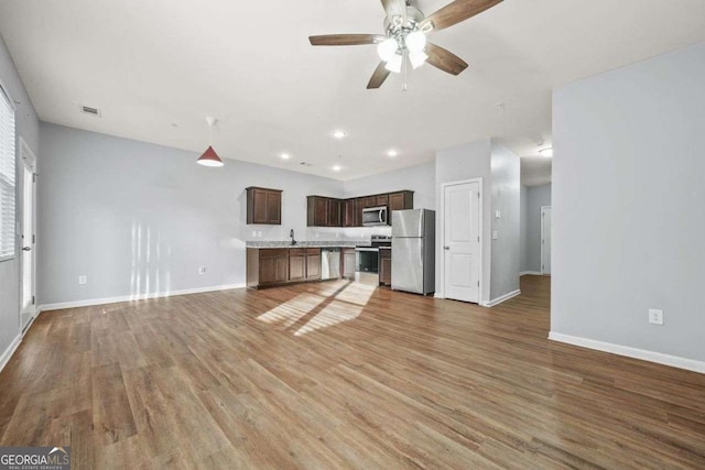 unfurnished living room featuring visible vents, ceiling fan, baseboards, and wood finished floors