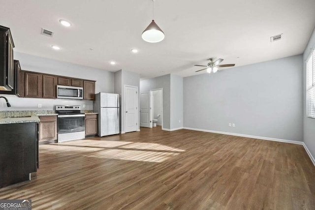 kitchen with stainless steel appliances, open floor plan, visible vents, and light stone countertops