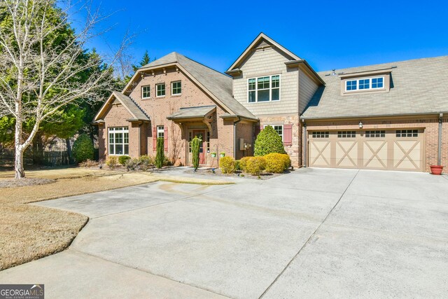 craftsman inspired home with a garage, concrete driveway, and brick siding