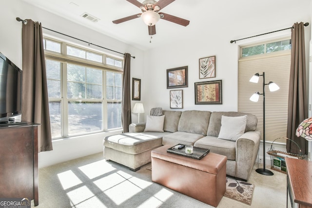 living room featuring light carpet, ceiling fan, visible vents, and baseboards