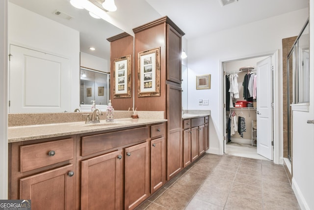 full bathroom with visible vents, tile patterned flooring, a walk in closet, vanity, and a shower stall