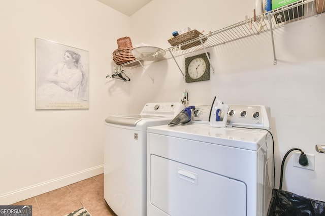 washroom featuring washing machine and dryer, laundry area, baseboards, and light tile patterned floors