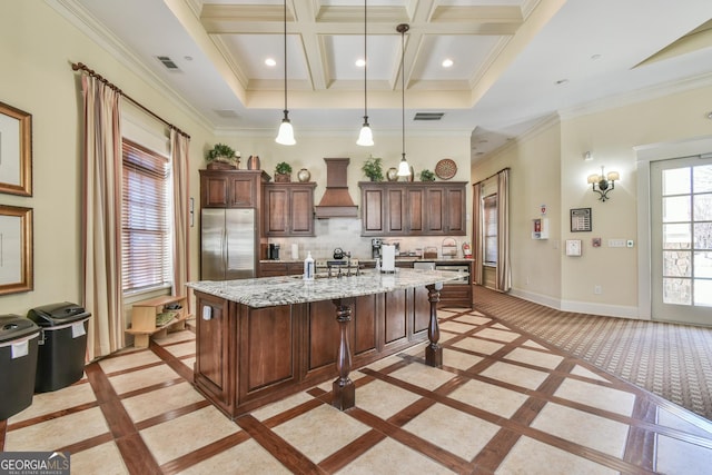 kitchen with a breakfast bar, pendant lighting, an island with sink, baseboards, and stainless steel refrigerator