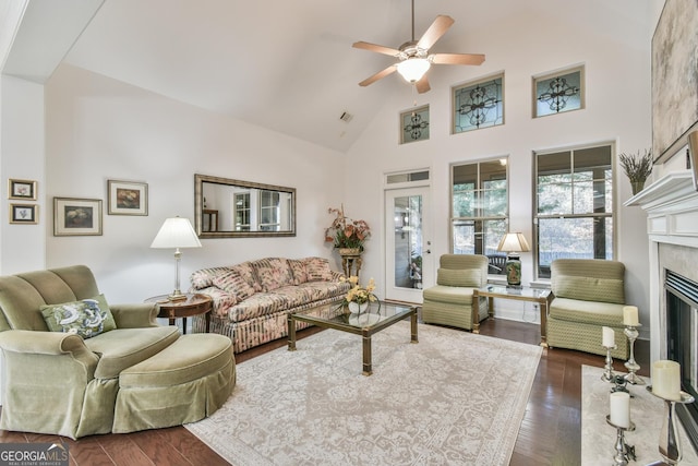 living room featuring dark wood-style floors, a fireplace, high vaulted ceiling, and a ceiling fan