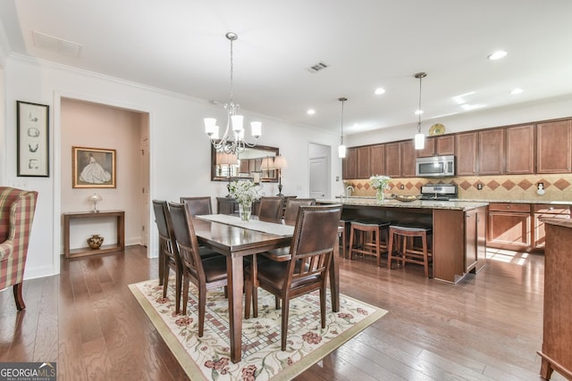 dining area with dark wood-style floors, baseboards, visible vents, and crown molding