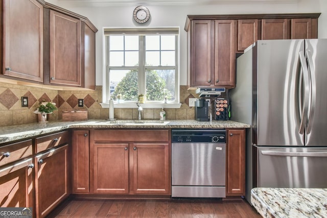 kitchen with tasteful backsplash, dark wood-style floors, appliances with stainless steel finishes, light stone counters, and a sink