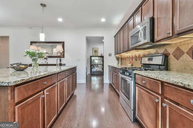 kitchen with appliances with stainless steel finishes, light stone counters, crown molding, pendant lighting, and backsplash