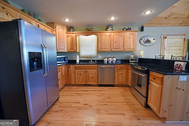 kitchen with light wood finished floors, appliances with stainless steel finishes, a sink, and recessed lighting