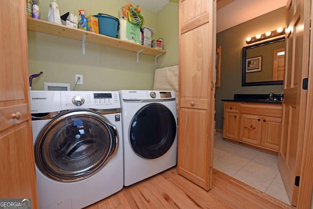 washroom with light wood-style floors, washer and dryer, laundry area, and a sink