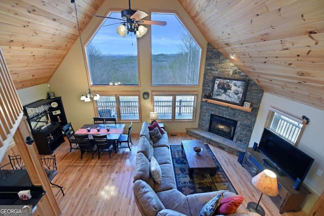 living area featuring a fireplace, wood ceiling, wood finished floors, high vaulted ceiling, and ceiling fan with notable chandelier