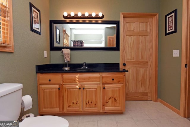 bathroom featuring tile patterned flooring, baseboards, vanity, and toilet