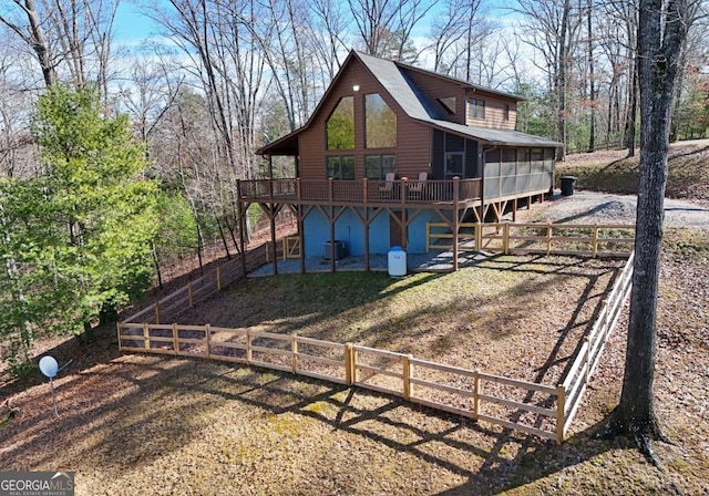 rear view of house with a sunroom, dirt driveway, and a wooden deck