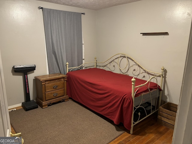 bedroom featuring a textured ceiling and wood finished floors