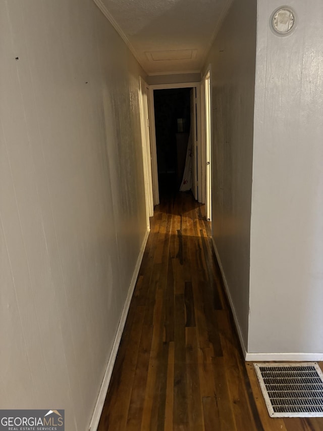 hall featuring visible vents, crown molding, baseboards, dark wood finished floors, and attic access