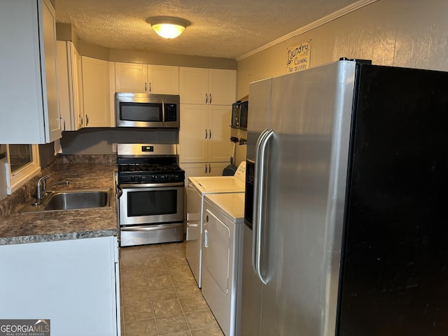 kitchen featuring stainless steel appliances, independent washer and dryer, a textured ceiling, white cabinetry, and a sink