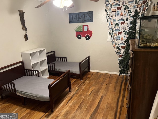 bedroom with baseboards, wood-type flooring, and ceiling fan