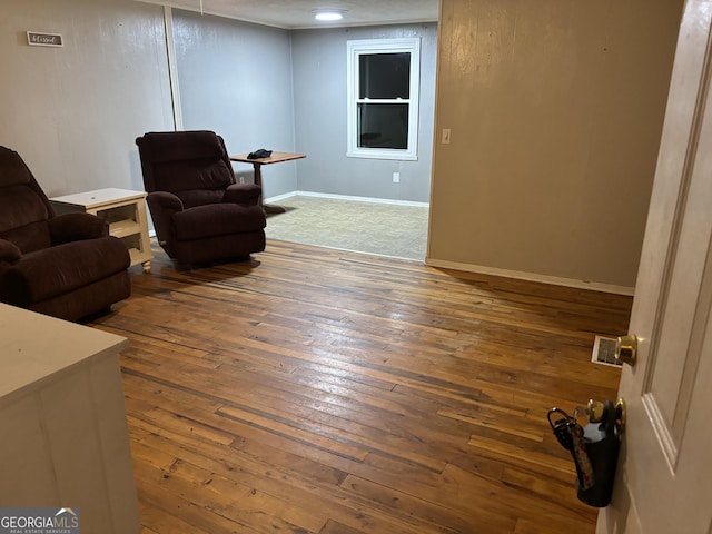 living area featuring visible vents, baseboards, and hardwood / wood-style floors