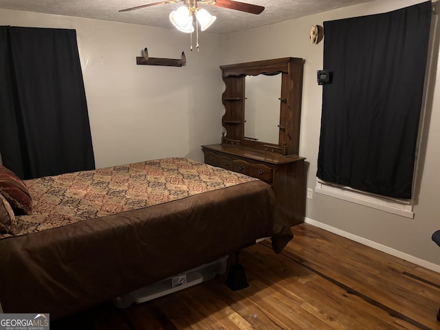 bedroom with baseboards, a textured ceiling, wood finished floors, and a ceiling fan