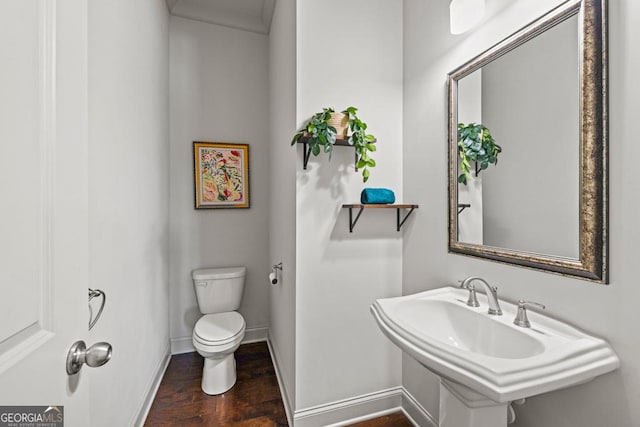 half bathroom featuring baseboards, a sink, toilet, and wood finished floors