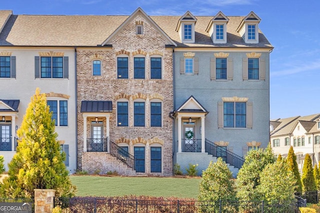 townhome / multi-family property featuring brick siding, a front lawn, and fence