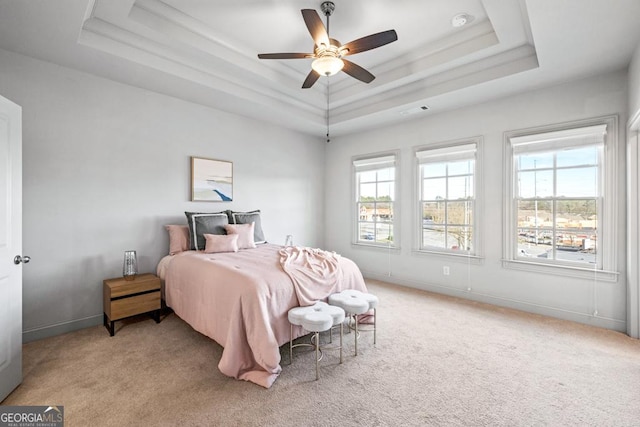 bedroom featuring light carpet, multiple windows, a raised ceiling, and visible vents