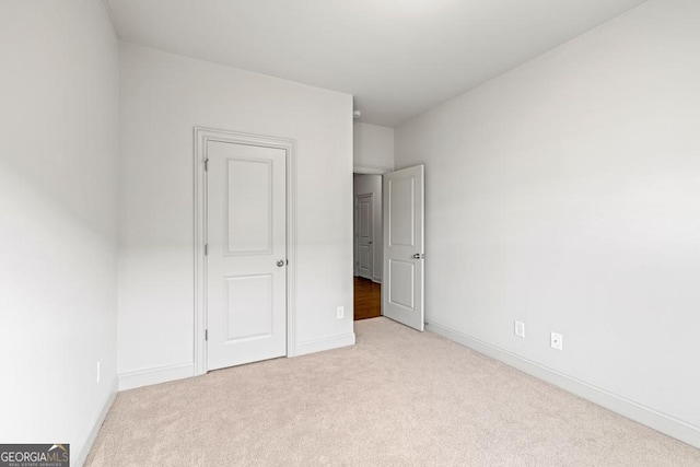 unfurnished bedroom featuring baseboards and light colored carpet