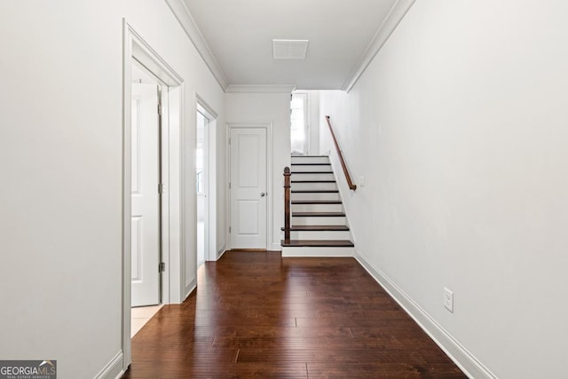 hallway featuring wood finished floors, visible vents, baseboards, stairs, and crown molding