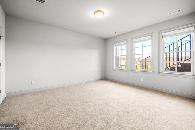 empty room with baseboards, carpet floors, visible vents, and a healthy amount of sunlight