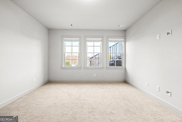 carpeted empty room with visible vents and baseboards