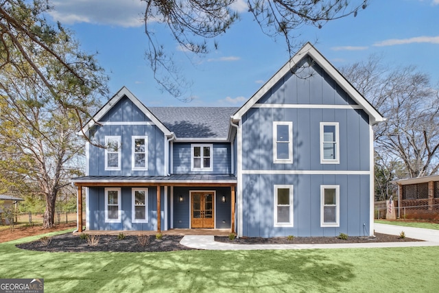 view of front of property with metal roof, a shingled roof, board and batten siding, a front lawn, and a standing seam roof