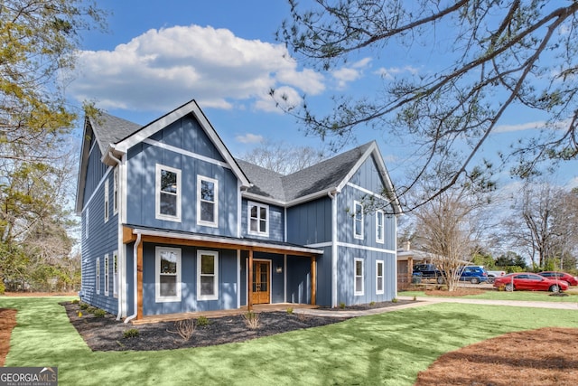 view of front of house featuring covered porch, a front lawn, and a shingled roof