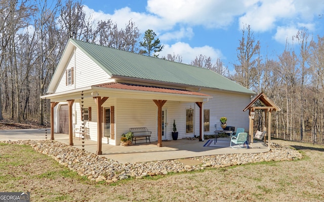 exterior space featuring a garage, metal roof, a patio, and concrete driveway