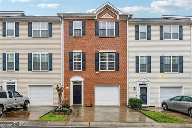 townhome / multi-family property featuring driveway, a garage, and brick siding