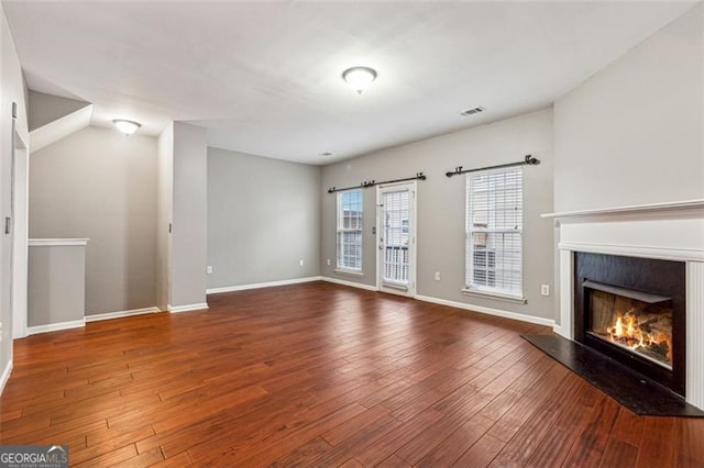 unfurnished living room with a fireplace, wood finished floors, visible vents, and baseboards