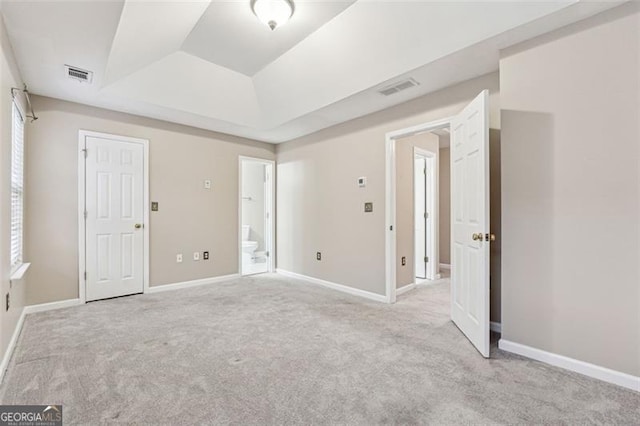 unfurnished bedroom featuring baseboards, visible vents, and a raised ceiling